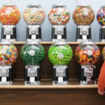 Small business owner restocking a candy vending machine business machine in an office break room
